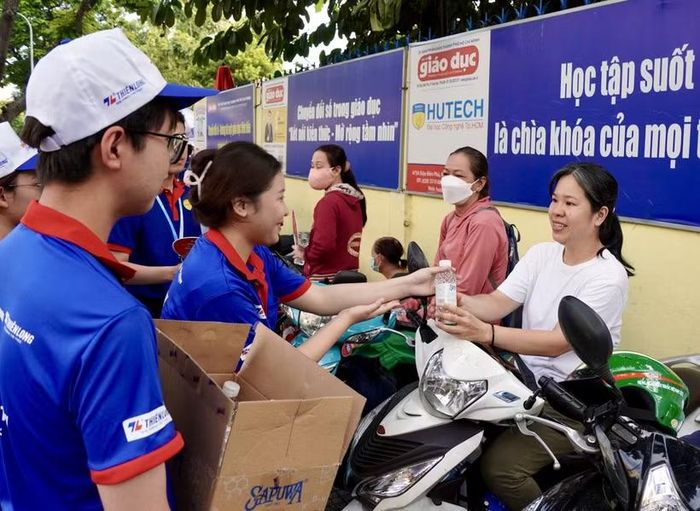 Sinh viên Trường Đại học Ngoại ngữ-Tin học TP Hồ Chí Minh hỗ trợ nước uống cho phụ huynh trong thời gian chờ thí sinh hoàn thành bài thi tại điểm thi Trường THPT Nguyễn Khuyến (phường Hòa Hưng). (Ảnh: Trung Tuyến/TTXVN)
