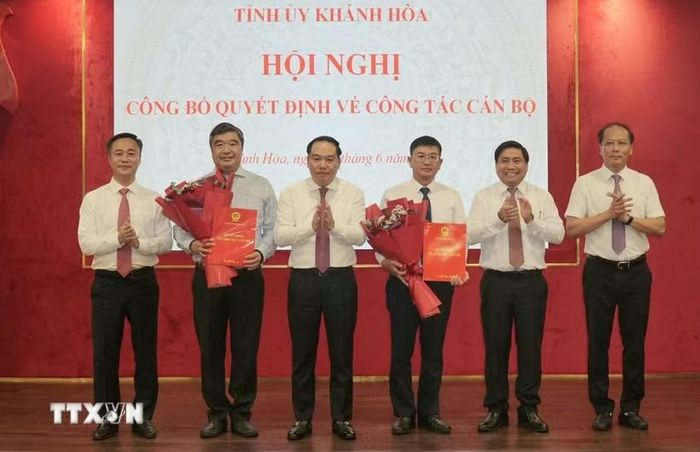 Thường trực Tỉnh ủy Khánh Hòa trao quyết định và tặng hoa chúc mừng ông Tạ Hồng Quang (bên trái) và nhà báo Lê Hoàng Triều (bên phải). (Ảnh: Xuân Triệu/TTXVN)