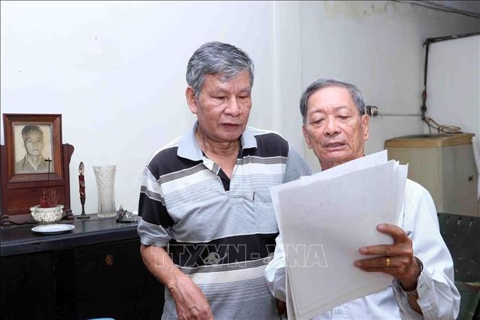 Cựu chiến binh Nguyễn Văn Tâm (trái) cùng đồng đội cũ đối chiếu tài liệu ghi chép về nơi chôn cất đồng đội.
