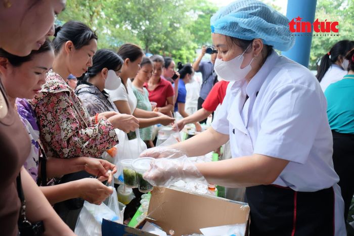 Hàng dài phụ huynh xếp hàng nhận cơm trưa miễn phí.