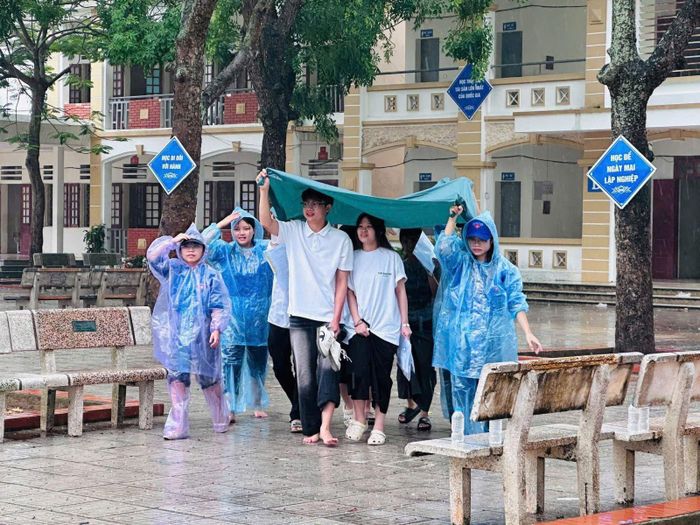 Sáng kiến dùng bạt lớn che chắn giúp nhiều thí sinh cùng lúc di chuyển qua sân trường mà không lo bị ướt.