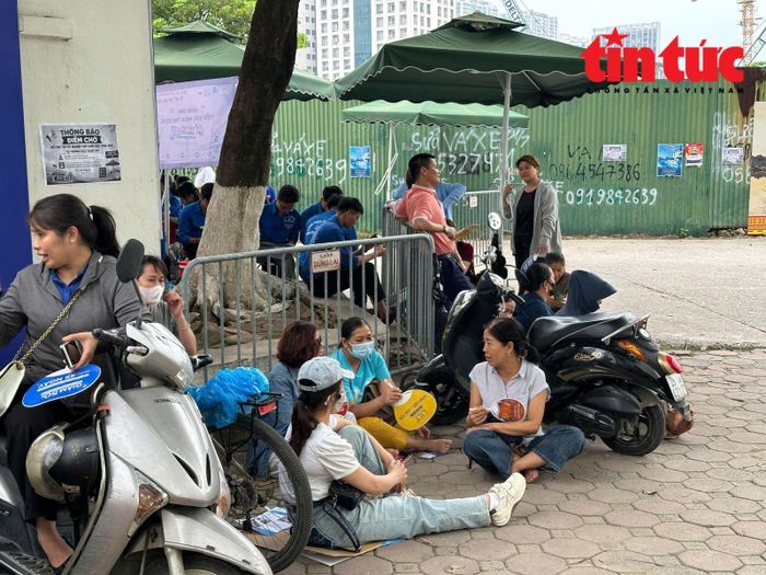 Điểm thi Trường THPT Trung Văn, nhiều phụ huynh ngồi bên vỉa hè chờ đợi các con.