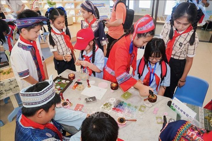 Thiếu niên nhi đồng hai nước Việt - Trung cùng nhau trải nghiệm văn hóa phi vật thể của Trung Quốc. Ảnh: TTXVN phát