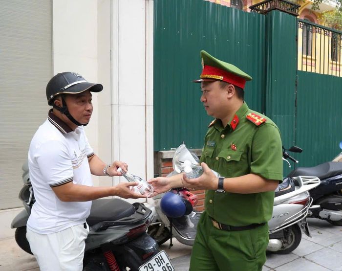 Các phụ huynh cảm thấy vui khi được một chiến sĩ Công an Hà Nội tặng nước uống miễn phí trong lúc chờ con đi thi.