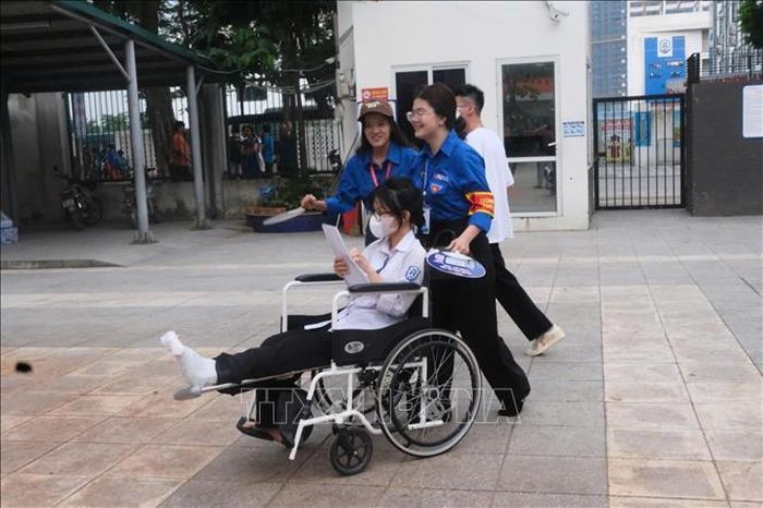 Thí sinh Nguyễn Thanh Bình (điểm thi Trường THCS Phú Thượng, phường Phú Thượng, Hà Nội) được các thanh niên tình nguyện hỗ trợ đưa vào phòng thi. Ảnh: Nguyễn Cúc/TTXVN.