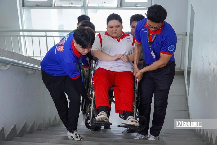 THCS Vân Đồn, phường Xóm Chiếu, lực lượng Tiếp sức Mùa thi đội hình Trường Đại học Nguyễn Tất Thành hỗ trợ thí sinh ngồi xe lăn vào phòng thi.
