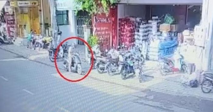 Lynh đi xe máy tới, xách trên tay vật nghi là can xăng rồi đi vào cửa hàng tưới lên hàng hóa. Ảnh cắt từ clip