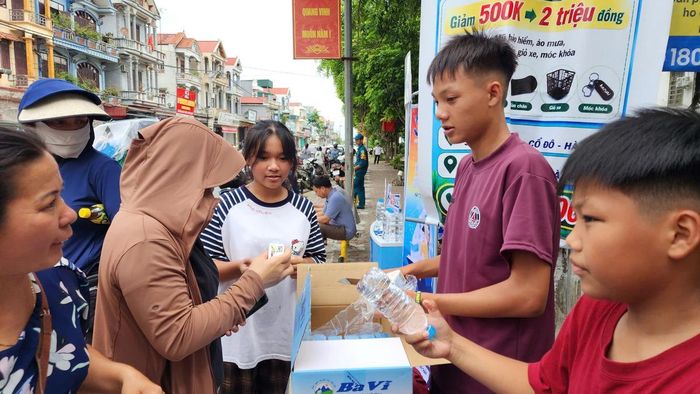 3 em nhỏ trao đến tận tay phụ huynh, thí sinh những chai nước mát.