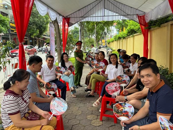 Phụ huynh vui vẻ nhận chiếc quạt "đa chức năng" rất hữu ích. Ảnh: T.L