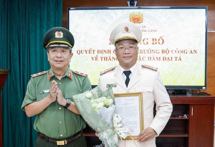 Trung tướng Đỗ Triệu Phong, Cục trưởng Cục Truyền thông CAND trao quyết định và tặng hoa chúc mừng TS. Nguyễn Đăng Khang - Phó Tổng Biên tập Báo Đại Đoàn Kết thăng quân hàm Đại tá. Ảnh: Quang Vinh.