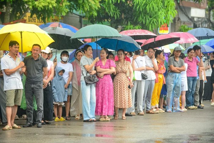Đúng 9 giờ 40 phút, tiếng trống báo hết giờ làm bài vang lên. Không khí bên ngoài các điểm thi lập tức trở nên nhộn nhịp hơn. Dưới mưa, nhiều phụ huynh nhanh chóng mở ô, tiến sát khu vực cổng trường để đón con.