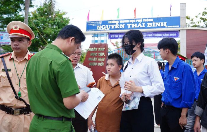 Lực lượng công an làm nhiệm vụ tại điểm thi Trường THPT Nguyễn Thái Bình (xã Thăng An) hỗ trợ kịp thời một thí sinh vào đúng phòng thi. Ảnh: HỒ QUÂN