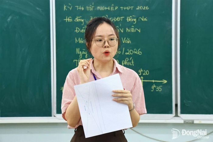 Giám thị hướng dẫn thí sinh gấp giấy thi đúng cách tại điểm thi Trường THPT Trấn Biên. Ảnh: Công Nghĩa