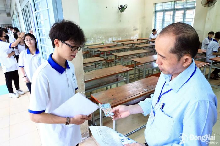 Giám thị đối chiếu thông tin của thí sinh trước khi vào phòng thi Trường THPT Trấn Biên. Ảnh: Công Nghĩa