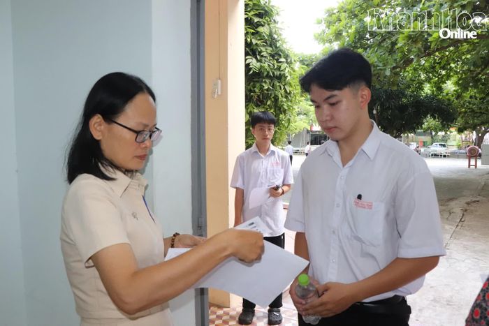Giám thị đối chiếu thông tin cá nhân của thí sinh trước khi vào phòng thi tại điểm thi Trường THPT Nguyễn Thiện Thuật.