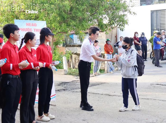 Tình nguyện viên tại điểm thi Trường THPT Tháp Chàm (phường Bảo An) tặng nước uống cho thí sinh.