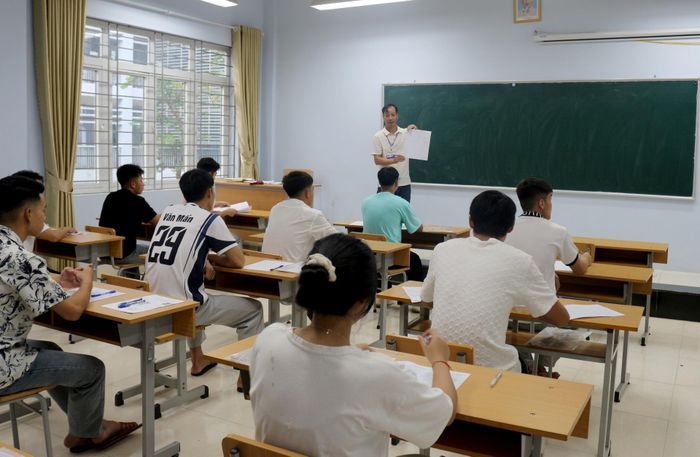 Giám thị hướng dẫn thí sinh điền thông tin vào giấy thi tại điểm thi Trường THPT chuyên Lê Quý Đôn.