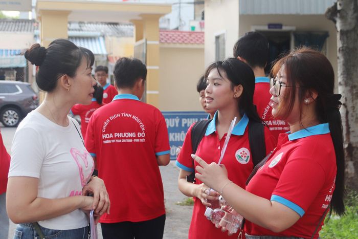 Bên ngoài điểm thi, giáo viên và các thành viên Đội Hoa phượng đỏ - Tiếp sức mùa thi có mặt từ sớm để hỗ trợ các thí sinh