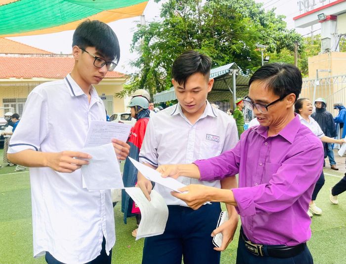 Thầy Nguyễn Đình Lành, giáo viên Toán, Trường THCS, THPT Lê Lợi xem đề thi và trao đổi với học sinh sau khi kết thúc môn thi