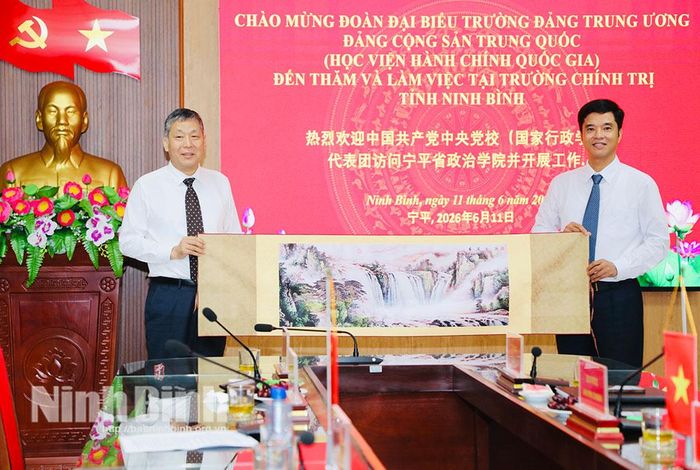 Đồng chí Đổng Chấn Hoa, Trưởng Ban Nghiên cứu và giảng dạy Chủ nghĩa xã hội khoa học, Trường Đảng Trung ương Đảng Cộng sản Trung Quốc trao quà lưu niệm cho đồng chí Phan Thành Công, Hiệu trưởng Trường Chính trị tỉnh.