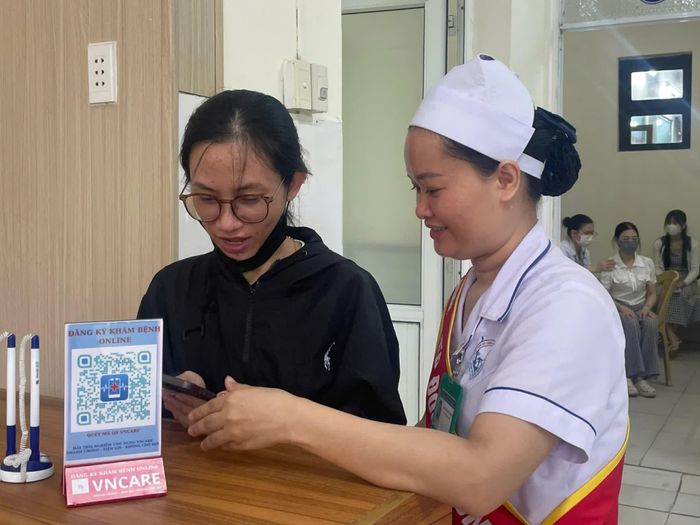 Nhân viên y tế hướng dẫn người dân đăng kí khám bệnh online - Ảnh: H.N