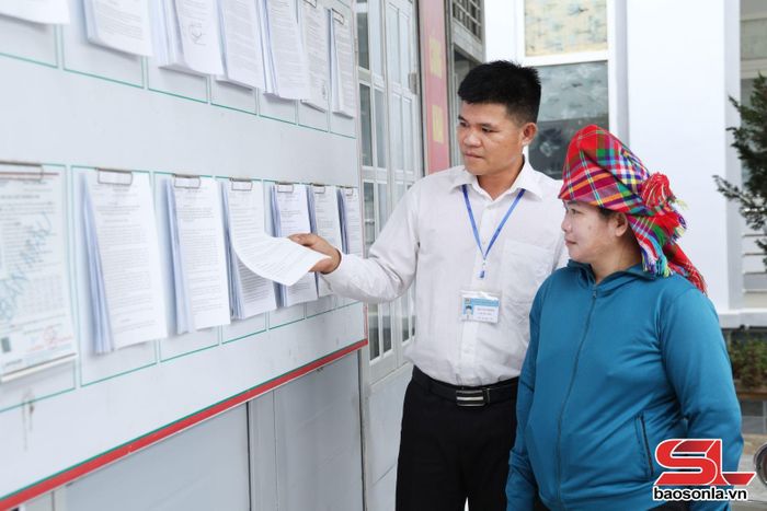 Cán bộ Trung tâm Phục vụ hành chính công xã Bó Sinh hướng dẫn người dân tra cứu quy trình giải quyết TTHC.