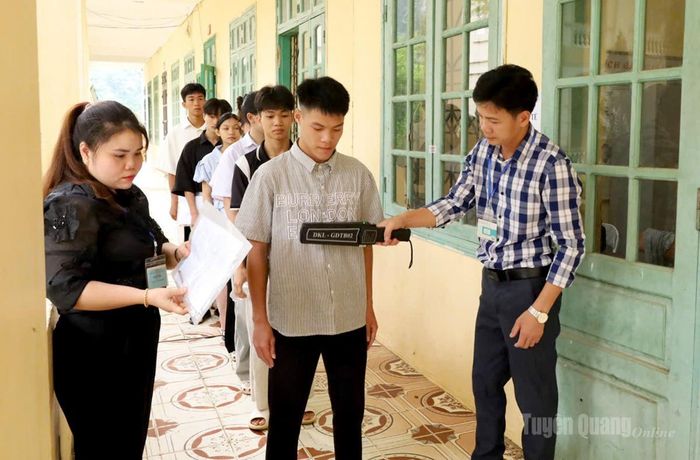 Lực lượng coi thi kiểm tra kim loại trước khi thí sinh vào phòng thi tại điểm thi trường THCS và THPT Thượng Lâm. Ảnh Như Quỳnh