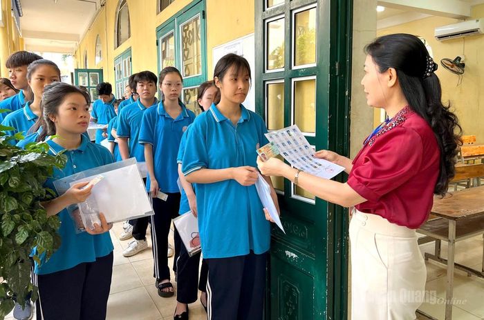 Cán bộ coi thi tại điểm thi trường THPT Ỷ La kiểm tra, đối chiếu thông tin thí sinh trước khi vào phòng thi. Ảnh: Thúy Nga