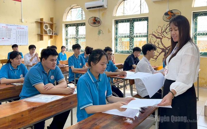 Cán bộ coi thi tại điểm thi trường THPT Ỷ La phát giấy thi và hướng dẫn thí sinh điền thông tin cá nhân. Ảnh: Thúy Nga