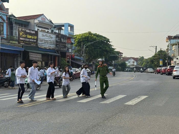 Công an xã Phú Lương hỗ trợ các thí sinh qua đường vào điểm thi.