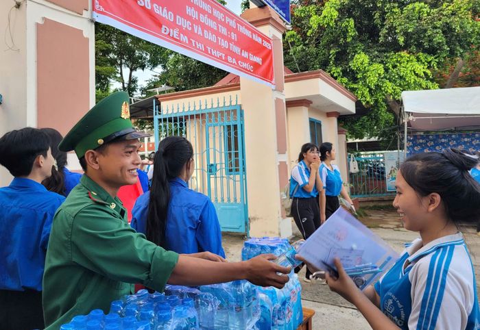 Chiến sĩ đồn Biên phòng Lạc Quới, phát nước uống cho các em học sinh trường THPT Ba Chúc. Ảnh: Tiến Vinh