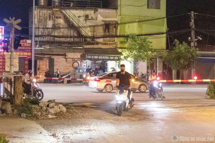 Không đội mũ bảo hiểm, một nam thanh niên khi vượt rào chắn đã đứng hẳn dậy với ý định quan sát tàu hỏa.