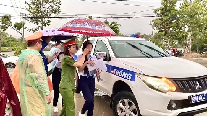 Lực lượng CSGT sử dụng xe chuyên dụng chở các em học sinh đến điểm thi đúng giờ trong lúc trời mưa.