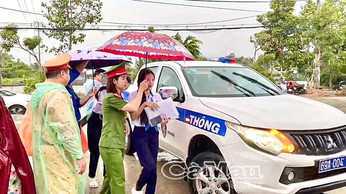 Lực lượng CSGT sử dụng xe chuyên dụng chở thí sinh đến điểm thi đúng giờ trong lúc trời mưa.