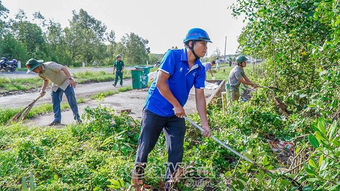 Các lực lượng tham gia phát quang cây cỏ, bụi rậm ven đường tại xã Đất Mũi, góp phần chỉnh trang diện mạo nông thôn