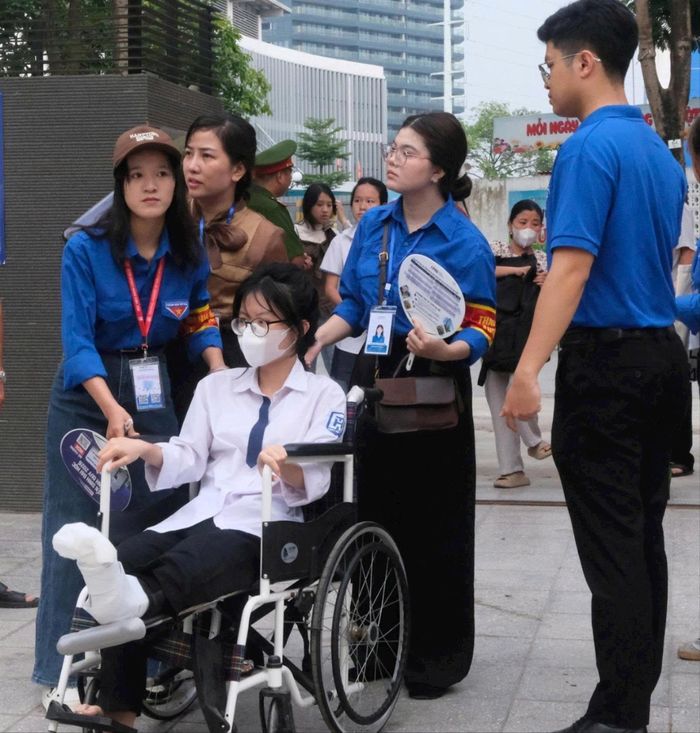 Thí sinh Nguyễn Thanh Bình được bà Âu Thị Hiền, Phó Trưởng điểm thi Trường THCS Phú Thượng và các thanh niên tình nguyện hỗ trợ rời điểm thi về nơi nghỉ sau môn thi đầu tiên. Ảnh: Tuấn Nghĩa