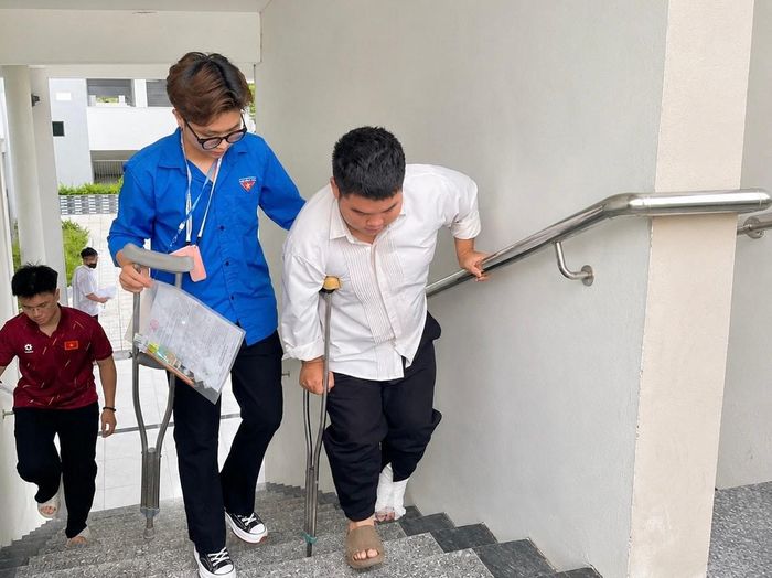 Một thí sinh bị chấn thương chân được lực lượng đoàn thanh niên hỗ trợ đến phòng thi.