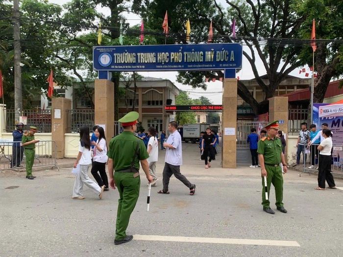 Lực lượng Công an xã Mỹ Đức trực phân luồng giao thông, bảo đảm an ninh trật tự tại điểm thi Trường THPT Mỹ Đức A. Ảnh: Biên Phạm