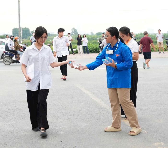 Tình nguyện viên phát nước uống tặng thí sinh trước khi vào trường thi. Ảnh: NS