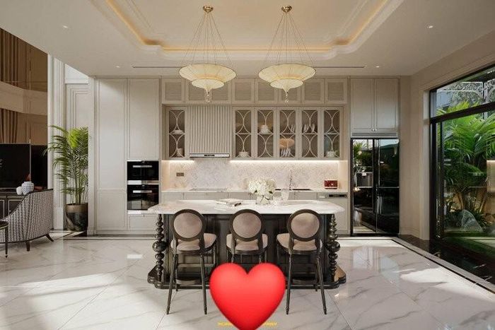 Không gian nhà bếp vừa hiện đại vừa mang hơi hướng tân cổ điển. Điểm nhấn của khu bếp là đảo bếp lớn, mặt đá marble với đường vân mềm mại. Hệ tủ bếp cao kịch trần được thiết kế thông minh với nhiều ngăn chứa đồ, giúp không gian luôn gọn gàng, sạch sẽ. Những cánh tủ kính với họa tiết uốn cong càng làm tăng tính thẩm mỹ.