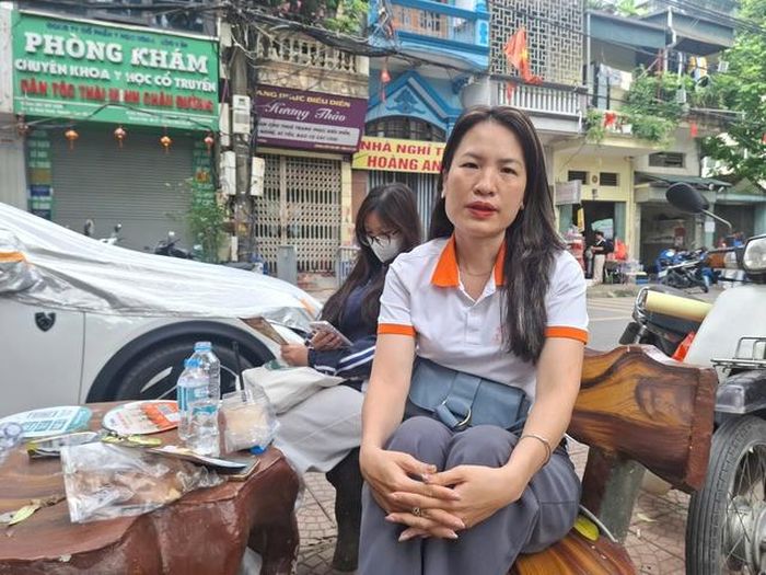 Chị Nguyễn Lê Tú Ngọc ngồi ngoài cổng trường chờ con gái. Ảnh: Quỳnh Mai.