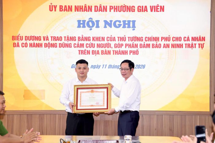 Ông Vũ Tiến Phụng - Phó Chủ tịch UBND TP Hải Phòng trao Bằng khen của Thủ tướng Chính phủ và tặng hoa chúc mừng hành động dũng cảm cho anh Phạm Thế Huy Hoàng. Ảnh: Việt Cường.