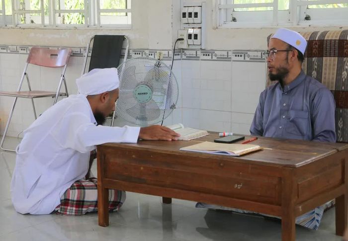 Học sinh người dân tộc Chăm ở cấp độ số 4 (đọc thuộc, đúng âm điệu Kinh Al-Qur’an và giáo lý Islam nâng cao) đang trả bài tập với thầy giáo sau mỗi tuần học