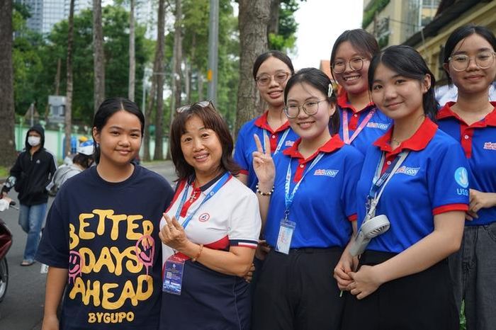 Chị Trương Thị Thanh Mỹ (thứ 2 từ trái) cùng con gái thứ hai hòa cùng không khí cổ vũ tại điểm thi. Theo chị, sự hỗ trợ của các tình nguyện viên giúp phụ huynh và thí sinh thêm tự tin trong kỳ thi quan trọng.