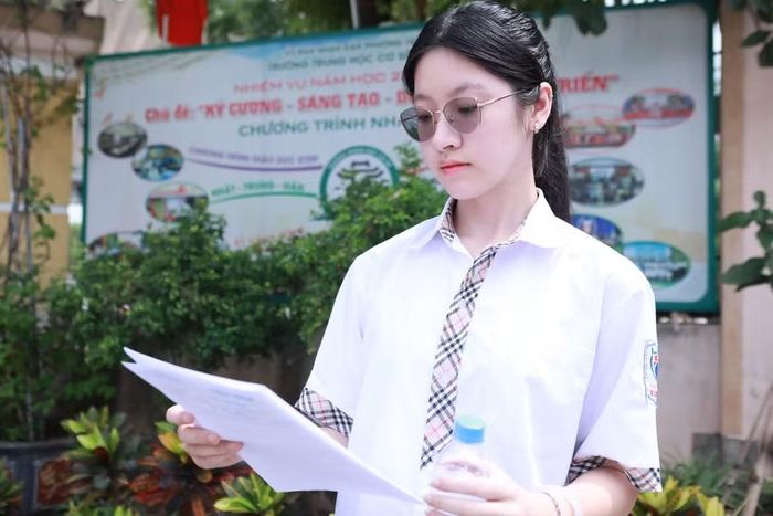 Thảo Vy xem lại đề Tiếng Anh và Lịch sử sau buổi thi cuối cùng sáng 12/6. Ảnh: Đình Tuệ.