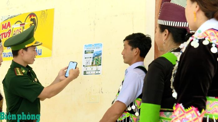 Cán bộ Đồn Biên phòng Tam Hợp, Bộ đội Biên phòng Nghệ An hướng dẫn người dân sử dụng điện thoại thông minh quét mã QR để gửi thông tin cho Bộ đội Biên phòng. Ảnh: Hải Thượng