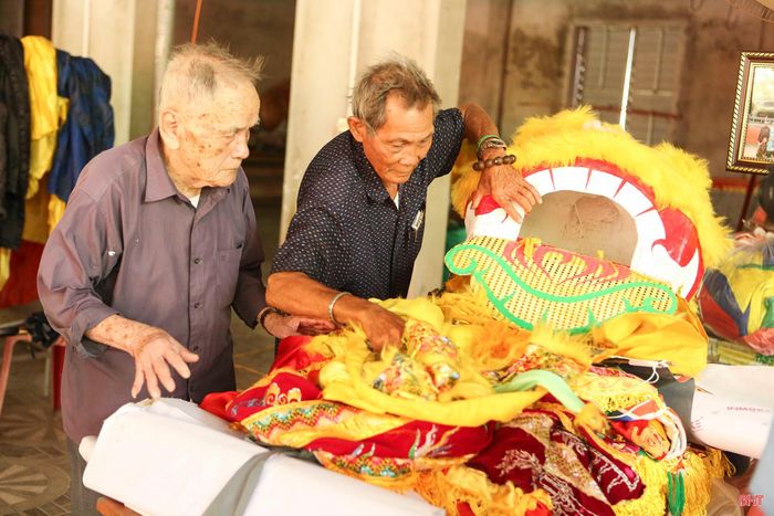 Cụ Lê Xuân Hoan (bên trái, trú thôn Tân Phong, xã Thạch Khê) cùng thành viên Ban Lễ nghi đền Nước Lạt soát lại đồ phục vụ rước lễ.