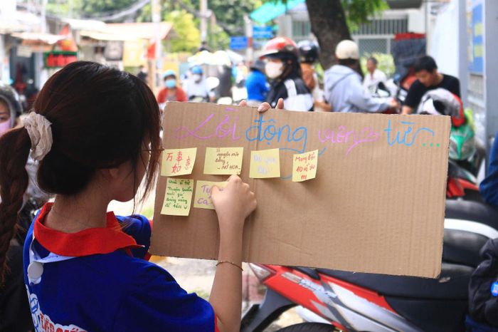 Em Minh Anh, sinh viên tình nguyện trường Đại học Sư phạm Kỹ thuật TP Hồ Chí Minh dán những lời động viên thí sinh khi đi thi.