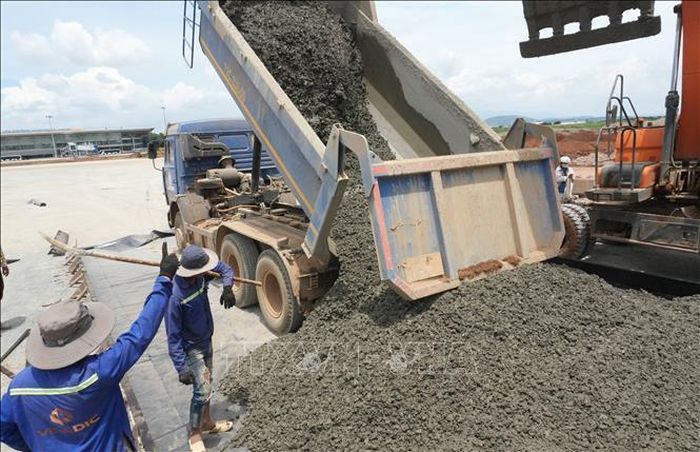 Dù giữa trưa nhưng các công nhân tích cực làm việc, đổ bê tông xi măng tại đoạn nối từ đường cất hạ cánh với sân đỗ máy bay.
