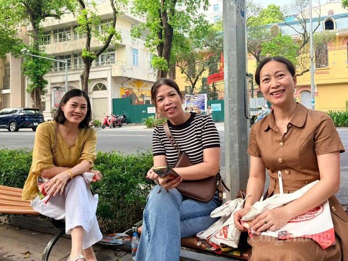 Các bậc phụ huynh lựa chọn ngồi dưới bóng cây hoặc khu vực có mái che để chờ con hoàn thành bài thi. Ảnh: Minh Hương